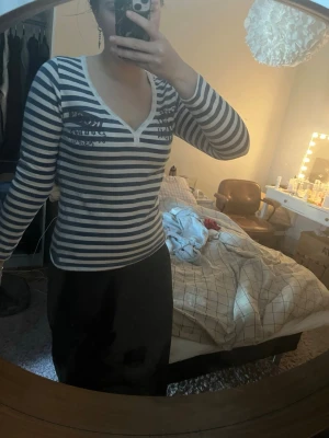 Randig långärmad topp med v-ringning - Säljer en långärmad topp med marinblå och vita ränder. Toppen har en snygg v-ringning och sitter figurnära. Perfekt till jeans eller kjol för en avslappnad men stilsäker look.