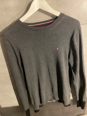 Mörkgrå stickad tröja Tommy Hilfiger - Extremt bra skick, märks inte att den är begagnad när du köper den! Passar S och M