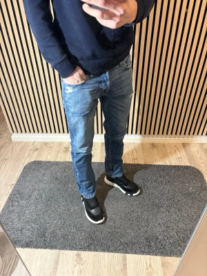 Hollister  - Säljer ett par ljusblå Hollister jeans med slitningar och hål vid fickan. Jeansen har rak passform och klassisk femficksdesign. Perfekta för en avslappnad och trendig look. Materialet är denim i bomull.