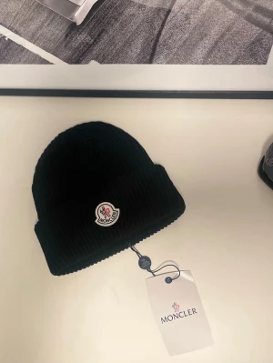 Moncler mössa  - Snygg svart Moncler mössa. Tveka inte med att kontakta vid frågor eller funderingar. Fraktar inom 12 timmar📦. Kom med bud priset är inte hugget i sten! Storlek: One size fits all. Köpt är Köpt👈👈