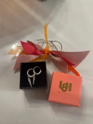 Silvriga örhängen från L8hasselblad - Säljer ett par silvriga örhängen från L8hasselblad med coola, spetsiga hängen. Örhängena har en modern design och kommer i original ask. Perfekt för dig som gillar unika accessoarer och vill sticka ut lite extra. Aldrig använda tyvärr men så så fina.