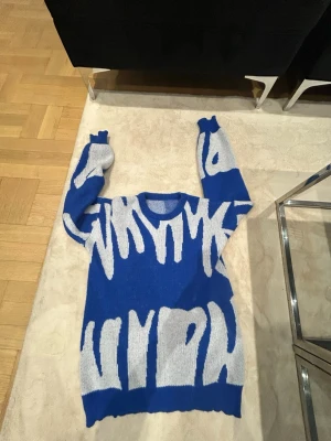 Blå stickad tröja med grafiskt mönster - Säljer en blå stickad tröja med unikt vitt grafiskt mönster. Tröjan har rund halsringning och långa ärmar. Perfekt för dig som vill sticka ut med en cool och modern look. Materialet känns mjukt och bekvämt.