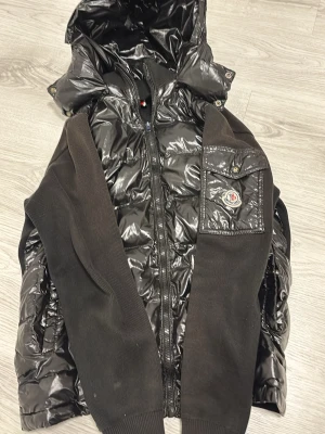 Moncler cardigan  -  DET ÄR ETT LITE HÅL VID MAGEN OCH LITE SMÅ SAKER PÅ RYGGEN INGET SOM SYNS OCH MAN KAN SÄTT EN SVART TAIP BIT DÄR FRAM DET ÄR DÄRFÖR JAG SÄLJER JACKAN BILLIGARE PRISET ÄR DISKUTETBART ✍️Snygg svart dunjacka från Moncler med glansigt yttertyg och stickade ärmar. Jackan har huva, dragkedja framtill och en bröstficka med Moncler-logga. Perfekt för kalla vinterdagar och riktigt trendig look. Vid snabb äffär kan jag gå mer i pris 