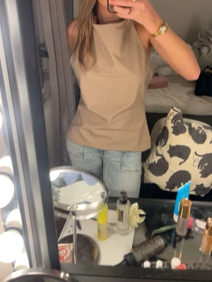 Beige openback linnetopp - Snygg beige linnetopp med hög hals och rak passform. Toppen är ärmlös och har en stilren, öppen i ryggen. Från Zara. Säljer för jag tyckten den var för stor på mig. Helt ny med lappen kvar. 