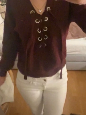 Vinröd stickad tröja med snörning - Vinröd stickad tröja med snygg snörning och metallöljetter framtill. 