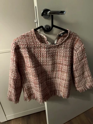 Rutig tweedtop från Zara - Trendig rutig topp från Zara i tweedmaterial med inslag av rosa, vitt och brunt. Toppen har trekvartsärm, råa kanter och dragkedja i nacken. Perfekt för dig som gillar en chic och modern stil.