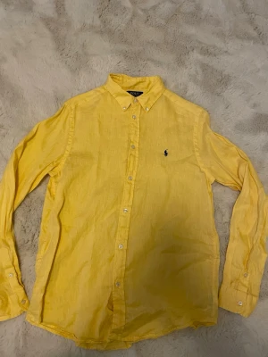 Gul linneskjorta från Polo Ralph Lauren - Säljer denna gula linneskjorta från Ralph lauren. Riktigt fet till sommaren.  Använd runt 10 gånger. Barnstorlek XL men passar som S. Kontakta vid frågor!!