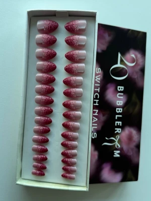 Switchnails x Bubbleroom press-on naglar rosa glitter - Snygga press-on naglar från Bubbleroom i en ask med 30 st. Naglarna har en mandelformad design i ljusrosa med glittereffekt i mörkrosa upptill. Tillverkade av återvunnet material och kan återanvändas. Perfekt för dig som vill ha trendiga naglar snabbt. Helt nya, bara öppnat för att ta bilderna 🌸