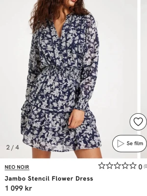 Mörkblå blommig klänning med volang - Supersöt mörkblå kortklänning med vitt blommönster, v-ringning och långa ärmar. Klänningen har smock i midjan och volangdetaljer i kjolen. Från neo noir