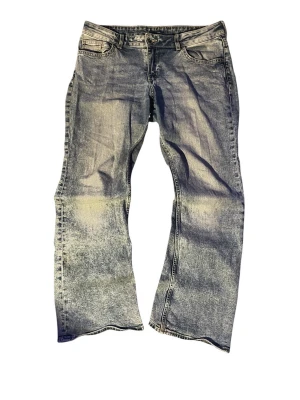 Blåa baggy jeans med slitningar - Baggy jeans i ljusblå denim med tydliga slitningar och tvättade detaljer. Modellen har raka, vida ben och klassisk femficksdesign. Perfekta för en avslappnad streetwear-look.