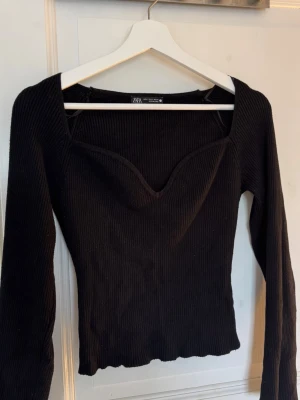 Svart ribbad topp från Zara - Snygg svart ribbad topp från Zara med lång ärm och v-ringad skärning. 