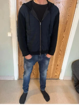 Polo hoodie - Snygg svart hoodie med dragkedja framtill och huva. Modellen har ribbade muddar vid ärmslut och nederkant samt en enkel, stilren design. Perfekt för en avslappnad och trendig look.