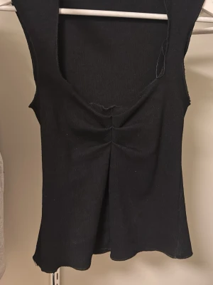 Svart snygg fest topp - Snygg svart ribbad topp med djup urringning och rynkad detalj framtill. Säljer då den inte används💕