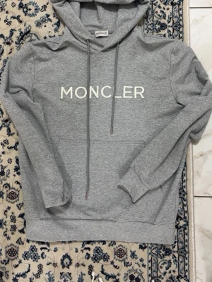 Moncler Hoodie - Grå hoodie från Moncler i nyskick. Aldrig använd. Klassisk modell med huva och stilren design i högkvalitativt material.
