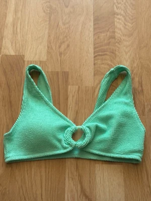 Mintgrön bikiniöverdel med ringdetalj - Snygg mintgrön bikiniöverdel i ribbad syntet med unik ringdetalj framtill. Sportig modell med breda axelband. Perfekt för strandhäng eller poolparty!