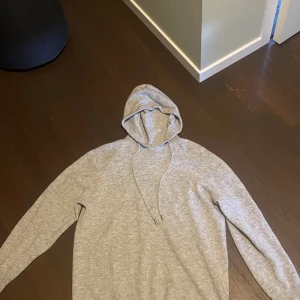 Grå merinoull hoodie  - En stilren grå merinoull hoodie men luva. Den har som ni ser på bild 2 en liten defekt längst ner på luvan men det är inget tydligt alls som man märker av. Nypris för 1000 kr och storlek är M men passar även L. Pris går och diskutera
