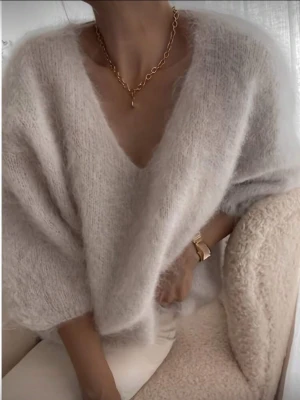 Ljusbeige fluffig stickad tröja - Supermjuk stickad tröja i ljusbeige med djup v-ringning och kortare ärmar. Tröjan har en fluffig, mohair-liknande känsla och är perfekt för lager-på-lager. Enkel och stilren design utan synligt märke. 
