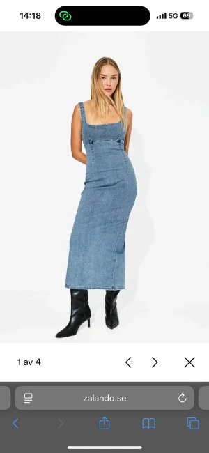 Blå lång jeansklänning med slits - Cool långklänning i blå denim med breda axelband och slits på baksidan. Klänningen har en figurnära passform och är ärmlös. Materialet är klassisk jeans och färgen är ljusblå.