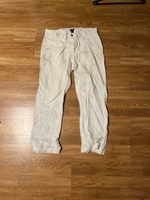 Vita linnebyxor från H&M - STRYKS INNAN FRAKT!!!Säljer ett par vita linnebyxor från H&M med avslappnad passform och dragsko i midjan. Byxorna har knappgylf och raka ben, perfekta för en chill och luftig stil. Materialet är linne vilket gör dem svala och sköna. Perfekt för sommaren 
