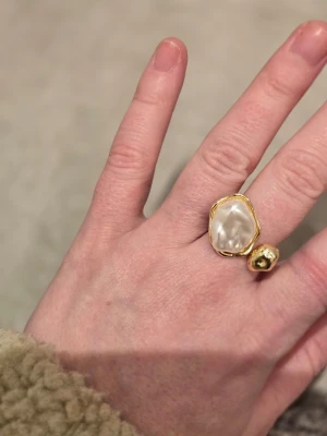 Guldfärgd med pärlor - En elegant ring i med pärla som dekoration. Ringen har en klassisk och stilren design som passar perfekt för dig som gillar subtila detaljer. Justerbar storlek 