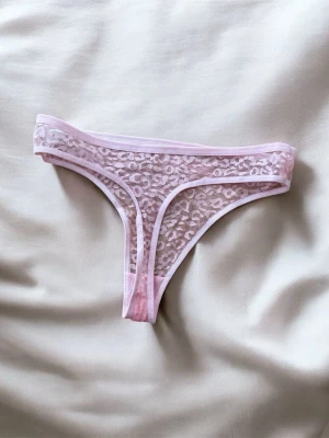 Ljusrosa spetsstring  - Säljer en ljusrosa stringtrosa i transparent spets.. Trosan har tunna kanter och en feminin design som känns både trendig och bekväm. Perfekt för dig som gillar detaljer och en lite sexigare look.