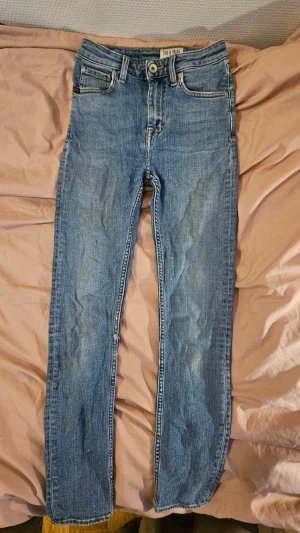 Skinny jeans från Tiger of sweden - Säljer ett par klassiska blå skinny jeans från Tiger of sweden med fem fickor och är midwaist. Jeansen har en ljus tvätt och subtila slitningar i bak vilket jag tycker är snyggt. Tillverkade i stretchigt denim för skön passform. Säljer då de är för små för mig men har definitivt varit mina favoriter