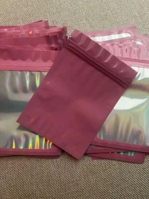 20 st Rosa holografiska zip-påsar, 15x10 - Säljer 20 stycken återförslutningsbara zip-påsar i metallic rosa med holografisk framsida. Perfekta för småprylar, smycken eller presenter. Påsarna är gjorda i plast och har en modern, glansig look som sticker ut. Storlek: 15x10