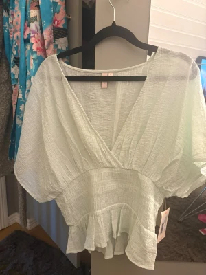 Ljusgrön omlott blus med volang - Säljer en Nelly topp som är slutsåld. Säljer för den e för stor 
