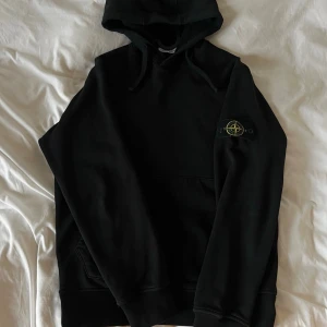 Svart hoodie från Stone Island - Säljer en svart hoodie från Stone Island med klassisk logotyp-patch på vänster ärm. Den är köpt i början av året i Bangkok flygplats. Kvitto med signatur finns, notera att priset är i baht (9380 baht ≈ 2700kr). Äkthet garanteras. Den är storlek L sitter som M.