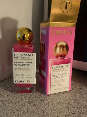 Truly Birthday Sex lyxig kroppsolja - Lyxig kroppsolja från Truly i doften Birthday Sex. Innehåller niacinamid, peptider, saffran, arganolja och hyaluronsyra. Oljan är vegansk och har en skimrande rosa färg med guldlock. Doftnoter av saffran, jasmin och ros. Flaskan rymmer 90 ml.