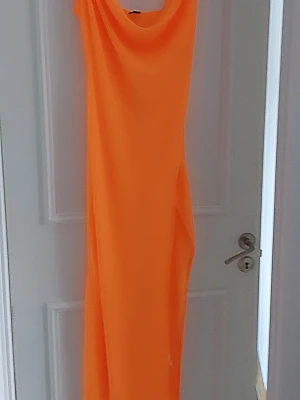 Orange strand  långklänning från SHEIN - Snygg orange strand  långklänning från SHEIN med draperad halsringning. Klänningen har en enkel och stilren design, perfekt för dig som vill sticka ut med en färgstark look. Tillverkad i ett mjukt och lätt material som ger en skön känsla.