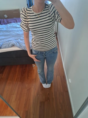 Randig puffärmad topp - Säljer en vit och svart randig topp med puffärmar och rund hals. Toppen har en slim passform och är gjord i mjuk bomull, perfekt för en trendig och avslappnad look.🩷