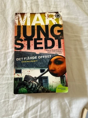 Det fjärde offret av Mari Jungstedt del 9 i Knutas serien - Spännande kriminalroman av Mari Jungstedt i pocketformat. Omslaget har en dramatisk design med inslag av orange, svart och grönt, och motiv av en motorcykel och ett hus. Boken utspelar sig på Gotland och handlar om mord och mysterier bland motorcykelklubbar. Del 9 i Knutas serien