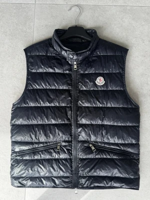Moncler gui väst - Säljer nu min Moncler gui väst i otroligt bra skick! Den är i färg marin blå och storlek S självklart äkta! Hör av er om frågor och pris går att diskutera🔥☀️