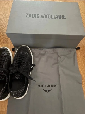Svarta glittriga sneakers Zadig & Voltaire - Säljer ett par svarta sneakers från Zadig & Voltaire med glittrig finish och vita sulor. Skorna har klassisk snörning och en stilren design. Vid frågor är det bara att höra av er🩷