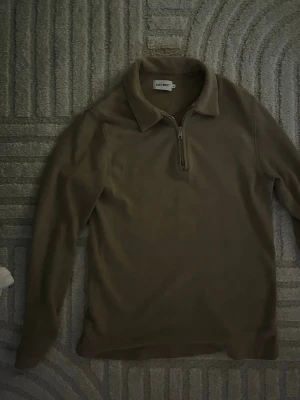 Beige ziptröja från EAST WEST - Säljer en beige långärmad ziptröja från EAST WEST. Tröjan har en klassisk krage och dragkedja framtill. Perfekt för dig som gillar stilrena och enkla plagg nu till sommaren!!