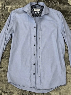 Ljusblå slim fit skjorta Bruun & Stengade - Ljusblå skjorta från Bruun & Stengade med slim fit-passform och snygg paisleymönstrad insida vid kragen. Skjortan har svarta knappar och är tillverkad i ett lättskött material. Perfekt för dig som gillar stilrena och moderna plagg. Storleken är 15/38 vilket motsvarar S/M. Perfekt för dig som är 175-180cm