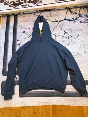 Mörkblå hoodie från Acne Studios - Stilren mörkblå hoodie från Acne Studios med klassisk huva och ribbade muddar. Perfekt för en avslappnad look och enkel att matcha med andra plagg. Mjuk bomullskänsla och minimalistisk design.