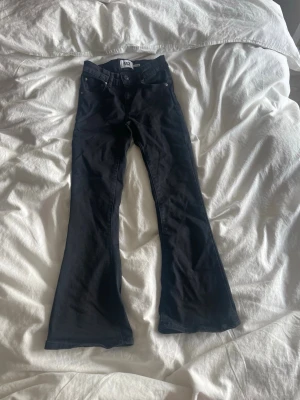 Svarta bootcut jeans från Dr. Denim - Snygga svarta bootcut jeans med klassisk femficksdesign och utsvängda ben. Jeansen har hög midja och är tillverkade i stretchigt denimtyg för en bekväm passform. Perfekta för en trendig och avslappnad look.