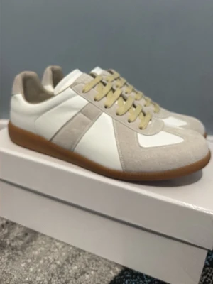 Vita och beige sneakers med mockadetaljer - Snygga sneakers i vitt och beige med ovandel i läder och mocka, samt beige snören och gummisula i brunt. Klassisk och stilren design som passar till det mesta. Perfekta för dig som gillar minimalistisk stil.