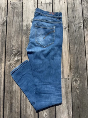 Dondup jeans - Säljer ett par snygga jeans från dondup, en riktigt snygg marinblå tvätt. Jeansen är i ett bra skick( ett litet hål/slitning på ena låret). Storlek:35. Hör av dig vid funderingar.