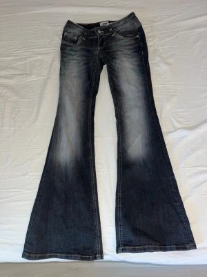 Mörkblå bootcut jeans från H&M - Snygga mörkblå bootcut jeans från lager 157 med slitningar framtill och bak. Jeansen har klassisk femficksdesign, låg midja och vida ben. Perfekta för dig som gillar retrostil och vill ha ett par jeans med cool tvätt.