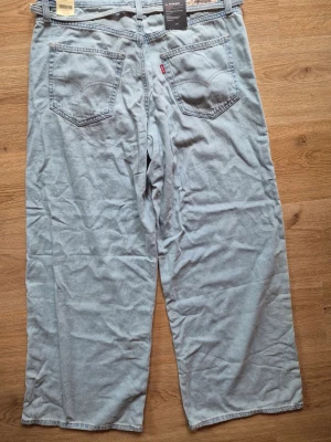 Ljusblå Levi's loose fit jeans - Säljer ett par ljusblå loose fit jeans från Levi's med raka ben och klassiska fem fickor. Jeansen har kopparfärgade nitar och Levi's ikoniska röda etikett på bakfickan. Tillverkade i slitstark denim, perfekta för en avslappnad stil.