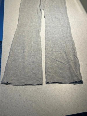 Grå mjukisbyxor från Gina Tricot - Säljer ett par ljusgrå mjukisbyxor från Gina Tricot. Byxorna har utsvängda ben och är gjorda i ett mjukt och stretchigt material som känns skönt mot huden. Perfekta för chill dagar hemma eller när du vill ha en avslappnad look.