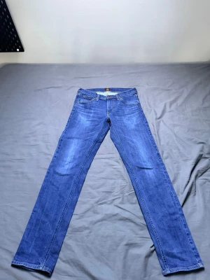 Blå raka jeans från lee - Säljer ett par klassiska blå jeans från lee med rak passform. Jeansen har fem fickor, normal midja och är tillverkade i slitstark denim. Perfekta för dig som gillar tidlös stil och vill ha ett par jeans som funkar till allt.