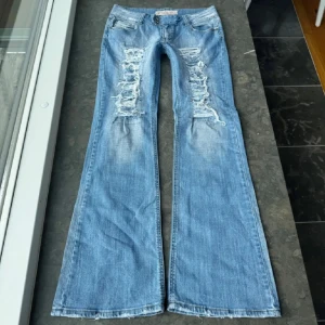Blå bootcut jeans med slitningar - Sjukt snygga lågmidjade bootcut jeans!!  Midjemått: 39 cm  Midjehöjd: 19 cm  Innerbenslängd: 80 cm 