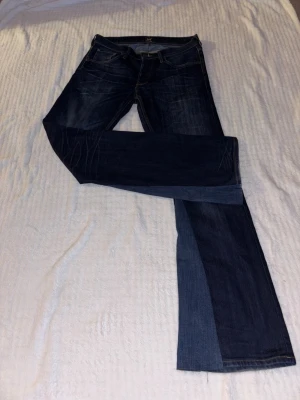 Mörkblå bootcut jeans från Lee - Säljer ett par mörkblå bootcut jeans från Lee med klassisk femficksdesign och kontrastsömmar. Innerbenslängd: 84 cm, midjemått: 42 cm rakt över