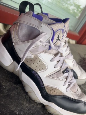 Air Jordan vit/lila/svart high sneakers - Säljer ett par Air Jordan sneakers i vitt, lila och svart med högt skaft. Skorna har mesh och läderdetaljer, perforerade partier för ventilation och klassisk Jumpman-logga på plösen. Snygga kontraster och cool retrostil som sticker ut.