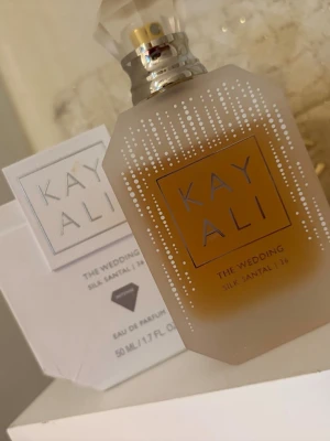 Kayali The Wedding Silk Santal 36 parfym - Kayali The Wedding Silk Santal 36 är en elegant parfym i en frostad, ljusbeige glasflaska med silverdetaljer och vita prickar. Flaskan har en lyxig, geometrisk form och rymmer 50 ml Eau de Parfum. Doften är exklusiv och modern.pris kan diskutera 