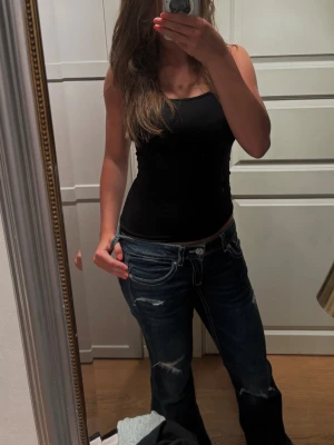 Mörkblå bootcut jeans med slitningar - Säljer ett par mörkblå bootcut jeans med snygga slitningar och kontrastsömmar. Jeansen har låg midja och klassisk femficksmodell. Perfekta för en avslappnad och trendig look. Storlek 164+ men passar xs-s. 🫶🏻